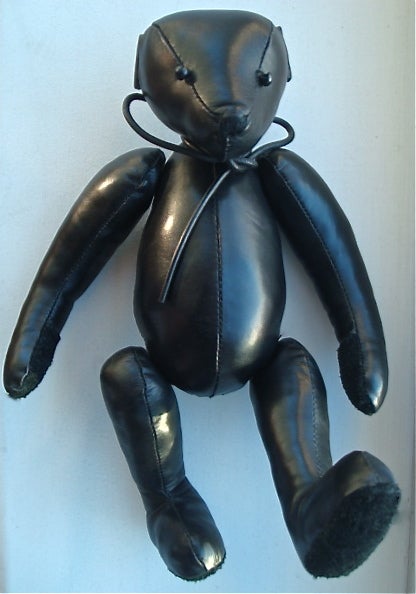 Comme Des Garcons 1990's black leather teddy bear with tie detail at neck.  Beaded eyes and suede applique nose, and paw details.  Limbs are able to move and rotate.  Jacquard design label at center back.