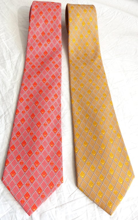 Unworn CHANEL PARIS set of 2 Citrus color anchor logo men's ties, one in tangerine the other in lemon yellow.  The ties feature a diamond grid pattern with anchor and monogram logo repeat.  Polished gold chain detail at reverse.

Tie length: