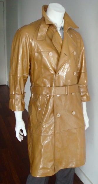 YSL YVES SAINT LAURENT Men's olive patent leather trench coat with polished gold finish hardwares.  Oversized pearl button closures.  Dual waist level pocket entry.  Adjustable, matching waist belt with logo engraved buckle.  Adjustable sleeve cuffs