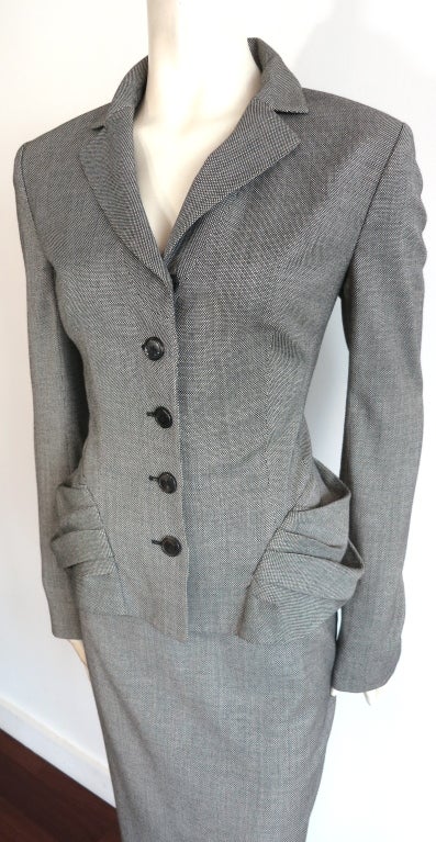 CHRISTIAN DIOR Gray birdseye virgin wool skirt suit lined in black silk.  Volume pleated, wrap around hip panel inspired by the 1950's signature new look.  Logo engraved button front closures with concealed top snap closure.

Jacket: Underarm to