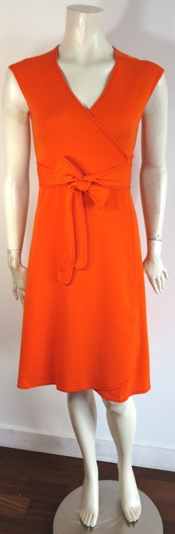 Vintage STEPHEN BURROWS 1970's tangerine knit jersey wrap dress with contrast red, zig-zag cover stitch detailing.  This excellent condition dress features a curved hem at opening front edge, with attached waist sash.

In mint condition with