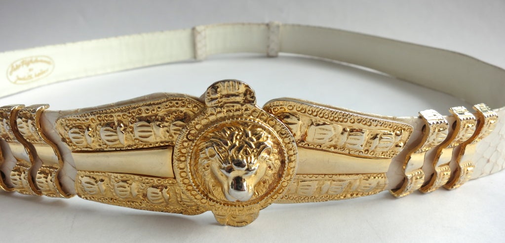 Vintage JUDITH LEIBER for Saks Fifth Avenue, 1960's Lion medallion ivory snakeskin belt.  Engraved metal front with triple bar attachment sides.  Polished gold finish with hook and bar closure.  The  back features double loops.

In excellent