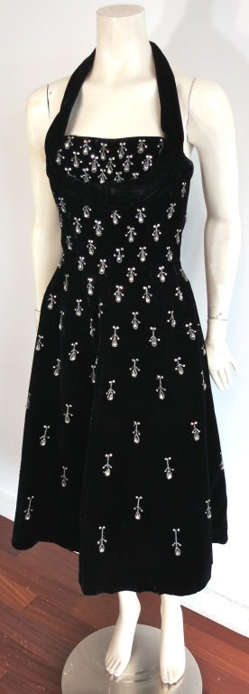 Vintage CEIL CHAPMAN 1950's teardrop rhinestone embellished black velvet halter dress.  

Boned bodice construction (as shown in the second to last photo) with draped circle, halter neck construction. 

 The embellishment  consists of teardrop