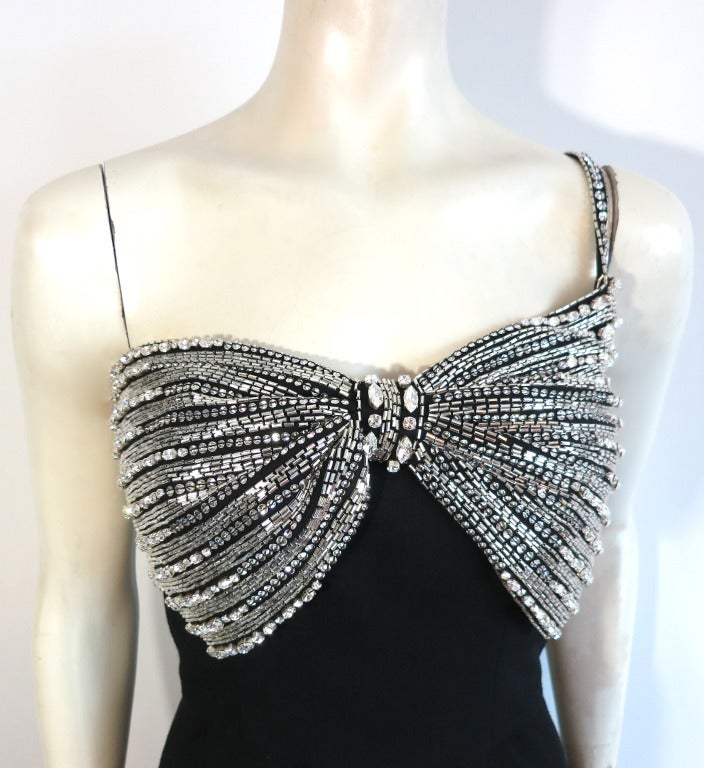 AZZARO PARIS Unworn embellished bow front cocktail dress in black wool crepe with an original retail price of $9,715.  

The sparkling crystal tone embellishments are created with alternating rows of diamond cut, cubic zirconia/clear crystal