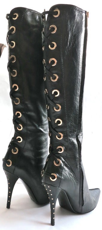 TOM FORD for YVES SAINT LAURENT Black leather knee high boots with oversized metal eyelet and leather lacing detail back.  Mini, metal stud heads at rear heels as well.

Long, inseam zipper closure with logo engraved metal zipper puller. 