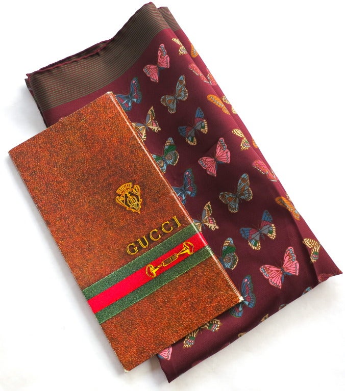 Vintage GUCCI ITALY 100% Silk butterfly printed scarf with the original outer card stock printed case.

Gorgeous dark burgundy ground with detailed, multi-color butterfly artwork.

Striped border with prominent logo at bottom center.

Made in
