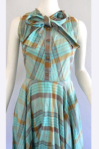 1950's CLAIRE McCARDELL sun dress in blue, green, and brown plaid stripes.  Light weight cotton voile fabric with button front placket, and neck bow tie detailing.

Bias cut, mitered top bodice with full circle skirt bottom.  Metal side seam