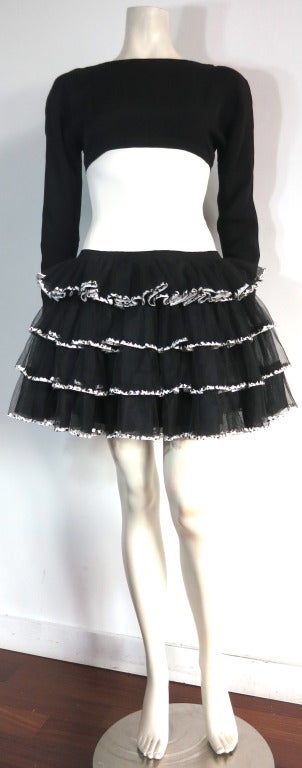 CHANEL PARIS Black & ivory embroidered tulle dress.  

This gorgeous, ballet inspired dress features a stretchy top, long sleeve bodice in black with ivory, inset waist panel.  

Tiered style, tulle bottom skirt with embroidered ivory motif on