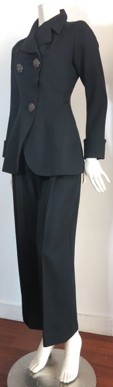 Excellent condition YVES SAINT LAURENT Black suit with crystal detail buttons.

The jacket features triple buttons at the front configured in a triangular placement.  The jacket has a fitted waist silhouette with wide sleeve cuffs.

The