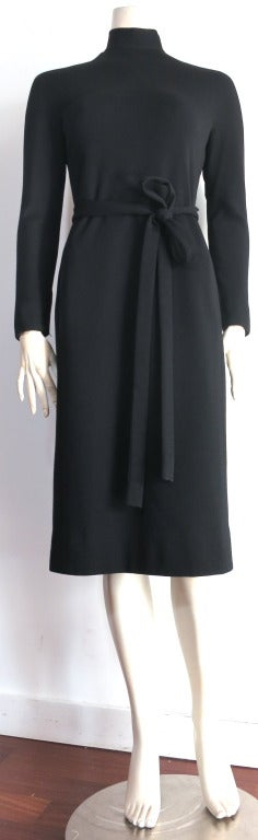 Excellent condition, NORMAN NORELL little black dress from the 1960's.

This classic Norell dress features signature, multi-button closures down the center back with self, knit waist sash.

Mock turtle-neck silhouette with side, waist level