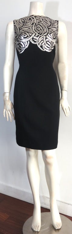 Excellent condition TOM AND LINDA PLATT Black crepe dress with platinum-tone sequins.

Scalloped edge neckline with artful, matte metallic sequin artwork at front and back top bodice.

Concealed, side seam zipper entry.

Fully lined in black,