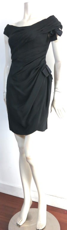 Gorgeous SCAASI ruched black silk cocktail dress.

This amazing dress features ruched construction radiating from the top left, draping down to the wearer's left.

Off-the-shoulder style neckline with satin, grosgrain ribbon, bow detailing at