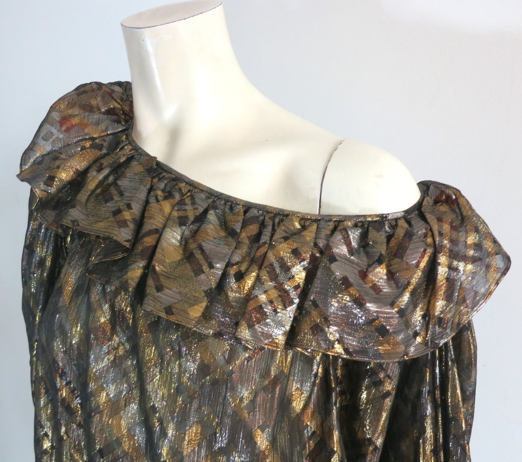 Mint condition YVES SAINT LAURENT Metallic silk peasant blouse.

The blouse was designed by Yves Saint Laurent in France, circa 1970.

The blouse is made of a semi-sheer black silk chiffon with metallic gold and silver plaid stripes cut on the