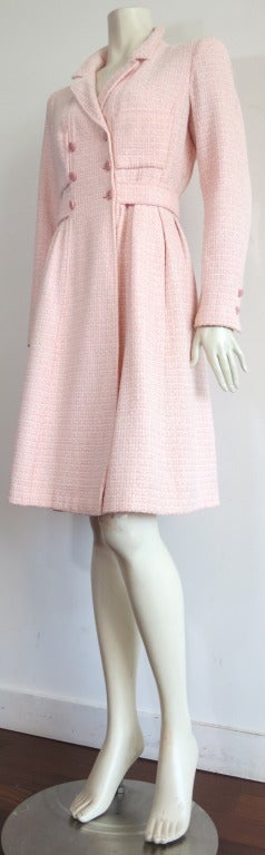 Beautiful CHANEL PARIS Pink & ivory melange boucle coat.

This gorgeous coat features a double-breasted front opening with metal logo centered, pink buttons.  

Twin chest pockets at front with belted waist detail at sides and back.  The center