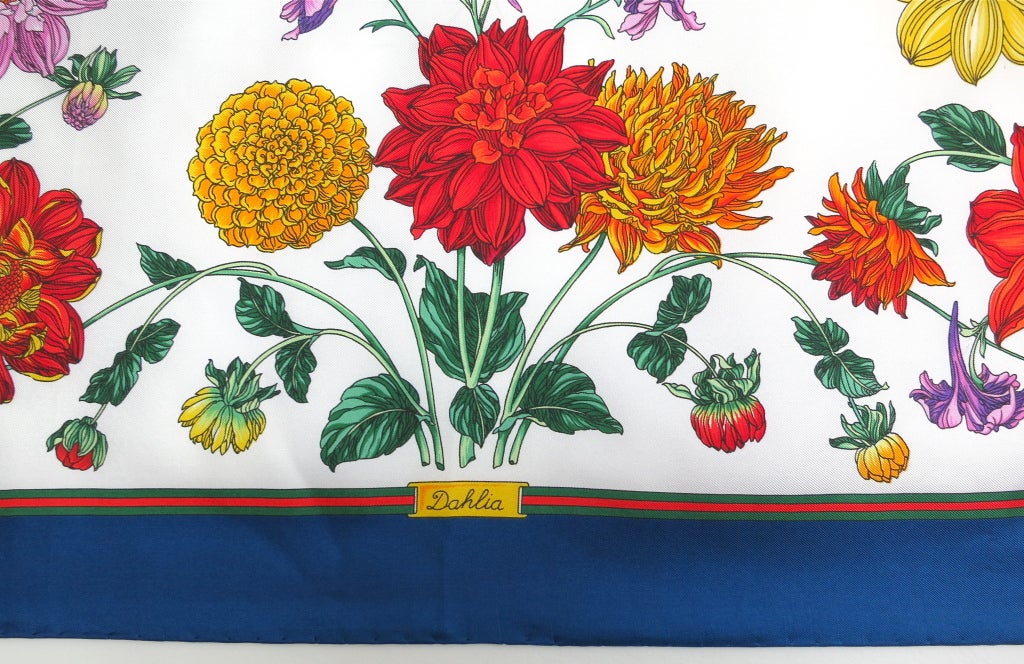 GUCCI Dahlia Flora printed silk scarf featuring detailed floral & butterfly artwork.  Signature monogram logo at top right and bottom left corners, with signature red & green border stripes.  Printed 'Dahlia' gold metal plate in the middle of the