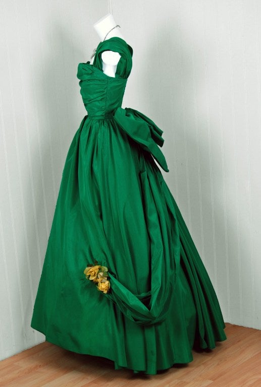 Magnificent 1950's gown fashioned from emerald-green taffeta. This evening dress is so fresh and youthful with its vibrant color and floral-applique! This beauty combines a fetching, girlish appeal with a woman's allure—a dynamite combination. I