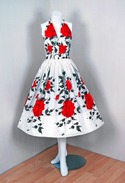 With its vivid red-roses cotton print and flawless silhouette, this sundress has the casual elegance the 1950's were known for. The halter bodice is both ladylike and sexy, cut to showcase your natural assets. The waist is a fitted nipped-hourglass