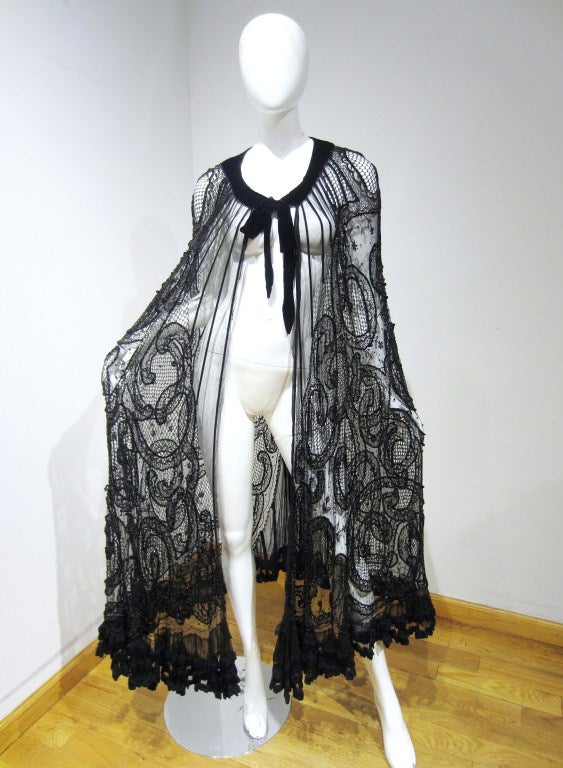 This dazzling mixed-lace Victorian cape is lavishly embellished with sparkling sequins and hand-done beadwork. The beaded pattern, subtle black-on-black design, appears abstract at first glance. When you look closer the exotic floral motif draws the