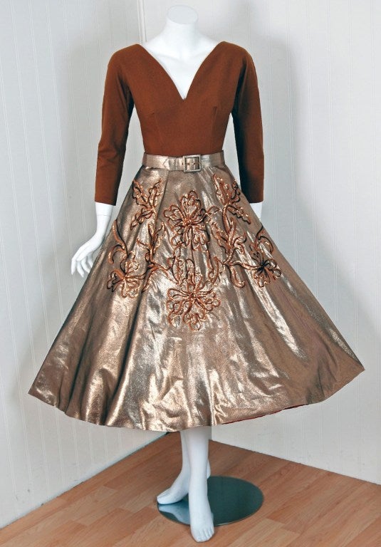 A gorgeous 1950's party dress that will light up any room! This alluring little number is made of an opulent metallic gold-lame with a feminine sequin-floral pattern woven into the fabric. This really gives the lame depth and a bit of a soft sheen