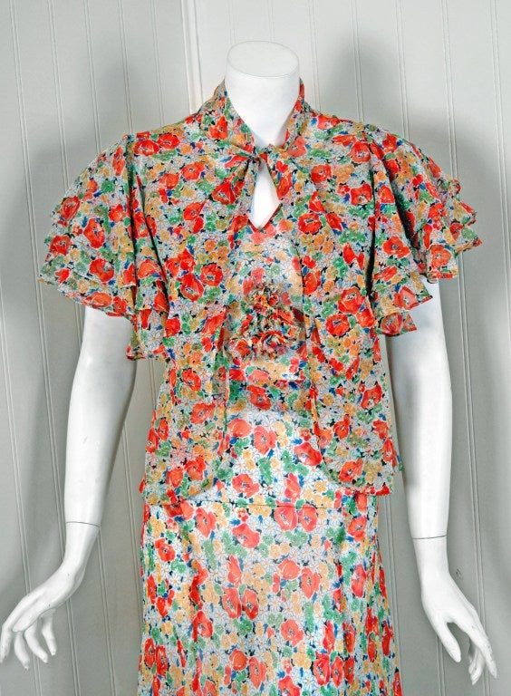 The breathtaking floral garden print used in this early 1930's silk-organdy dress ensemble has a fresh innocence that I find irresistible. The bodice is a low-cut plunge sleeveless accented by a beautiful 3-D applique. The belted nipped waist falls