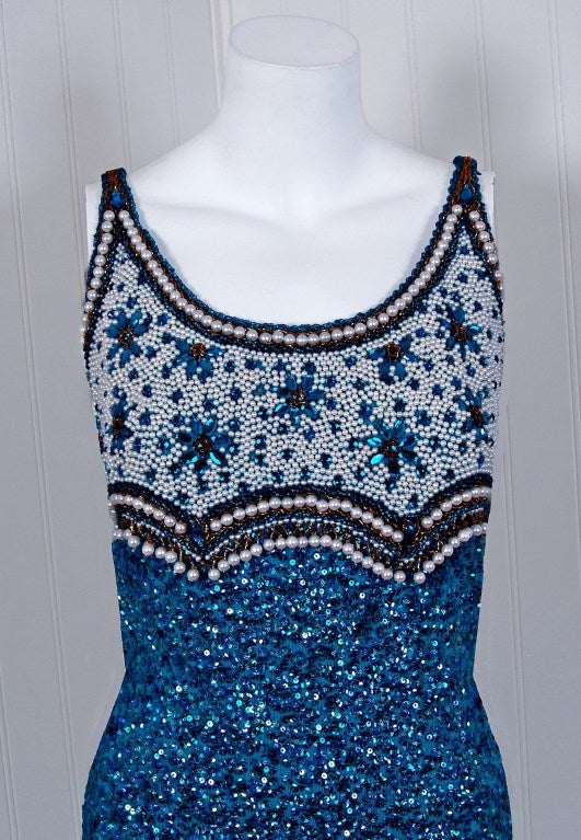 1950's Gene Shelly designer garments are in a class of their own. They are always fully-sequined by hand and fit to flatter the figure. This treasure has a fantastic shelf-bust design worked in, featuring pearl-beadwork around royal-blue jewels. The