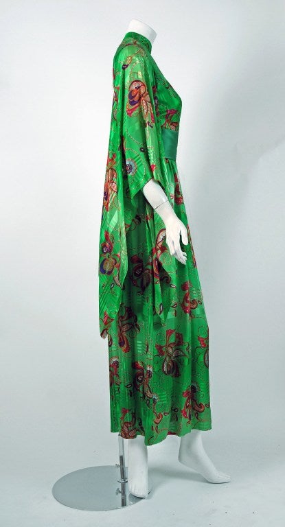 A wonderful and extravagant 1970's Mollie Parnis gown in a bold emerald-green psychedelic pattern. The base of the dress is one long and lean sheath in 