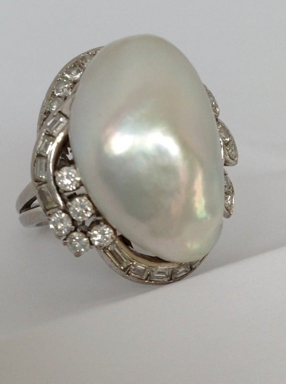 Elegant 1950's baroque pearl set in platinum with a beautiful diamond setting. The pearl has a beautiful lusters and was not cut to set, but set in its entirety. 
Such a classic, so so chic. 
The form and design are exquisite. 
From day to