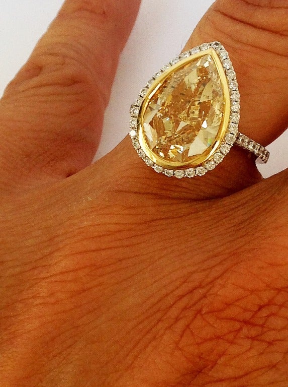 Elegant large 6.11 pear shape diamond solitaire,with fancy light yellow hue, W-Z, at least, Si2-Si3, set in 18 k white gold setting with diamond halo and detail along sides of shank.
Beautiful brilliance and fire. So so attractive on the fingers, a