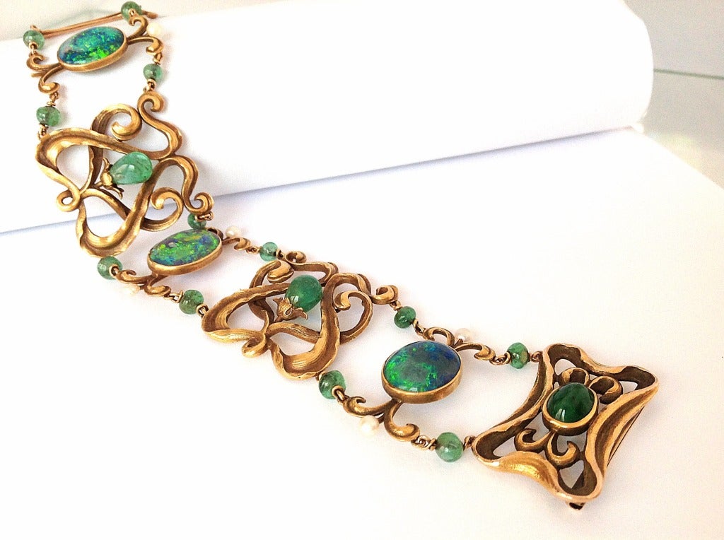 Spectacular Art Nouveau Period bracelet, with three magnificent Large black opal cabochon, which have splendid rich fire, accented by natural emeralds, set in intricately crafted gold with pearl accents. Part of a private estate, this piece was