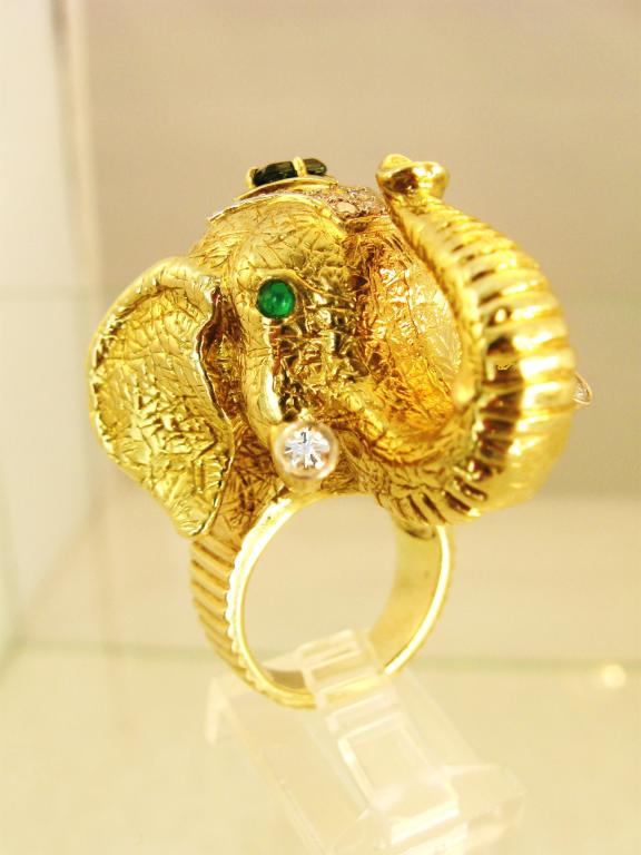 Superbly bold and dense, 18k gold elephant head ring. Head creates a large dome style ring, with diamond tiara on top of head with center emerald , emerald cab eyes and brilliant cut diamonds at the end of each tusk. Wonderful transition piece from