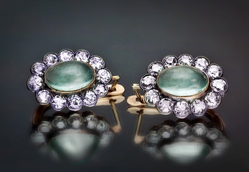 These antique earrings were handcrafted in Moscow between 1908 and 1917. 

Each earring is set with one central cabochon cut aquamarine in a gold millegrain bezel with an approximate weight of 2 carats, 
surrounded by 12 old European cut diamonds