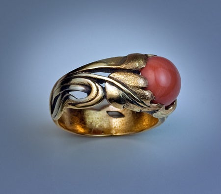 A finely modeled Art Nouveau floral-design openwork gold ring with a cabochon coral.

The ring is crafted in textured and polished gold.

Width - 11 mm (7/16 in.)

Weight - 10 g

US ring size 8 3/4 (19 mm)