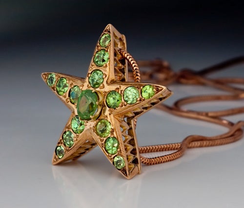 Originally, a star brooch, it has been converted into a slider pendant. 

The rose 14K gold five pointed star is set with sixteen sparkling apple green Russian Uralian demantoids.

The pendant comes with a modern 14K rose gold snake chain.
