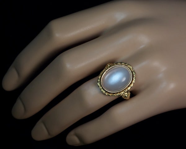 Russian, made between 1908 and 1917.

The ring features a large cabochon cut oval moonstone ( 18 x 14 mm) framed by a ribbon tied laurel wreath bezel flanked by scrolling shoulders.

Height  21 mm (7/8 in.)

US ring size 9 3/4  (19 mm)

The