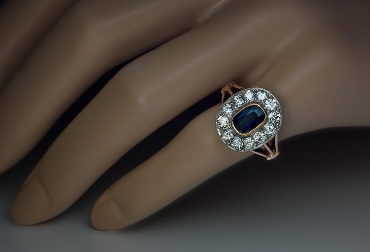 The ring is handcrafted in 14K rose gold. 

The center stone is a natural midnight blue sapphire ( 7.5 x 5.1 x 3.05 mm,  approximately 1.70 ct) set in a gold millegrain collet setting, encircled by 12 old European cut diamonds set in silver over