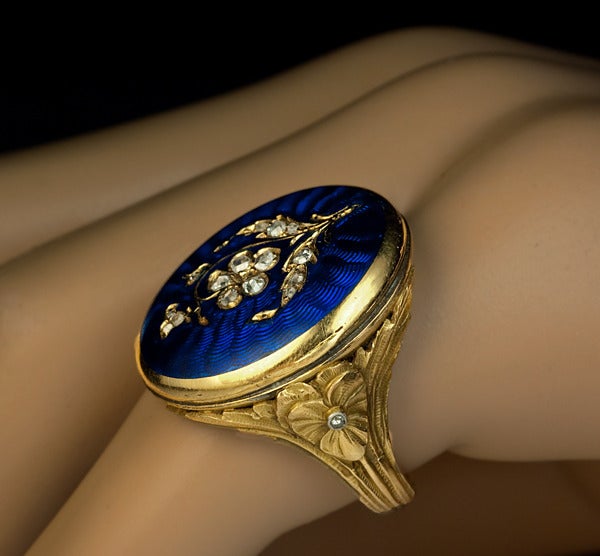 Victorian Era Antique French Locket Ring

circa 1890

The cover of the secret compartment is decorated with a diamond flower (rose-cut diamonds) on a royal blue guilloche enamel ground. 

This type of rings is also known as poison
