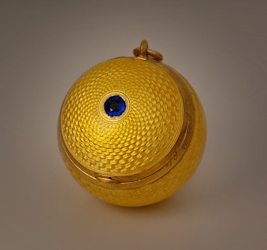 Made in St. Petersburg between 1908 and 1917 by the 3rd Jewelry Artel.

The ball shaped gilded silver locket is completely covered with beautiful golden yellow guilloche enamel of exceptional quality.

The 3rd Jewelry Artel specialized in fine