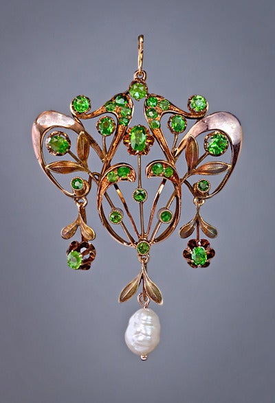 A polished rose and matte green 14K gold openwork floral pendant features twenty eight vibrant green Russian demantoid garnets and a beautiful baroque pearl.

This delicate Art Nouveau pendant was handcrafted in Moscow between 1908 and 1917.

It