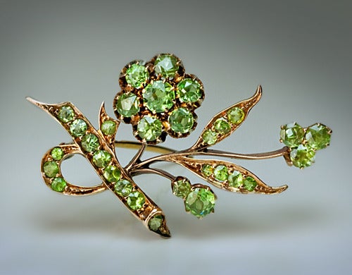 The brooch is designed as a flower in the Art Nouveau taste of the period, handcrafted in 14K rose gold, set with apple green Russian demantoid garnets from the Ural Mountains.

The brooch is marked  on the frame with 56 zolotnik gold standard