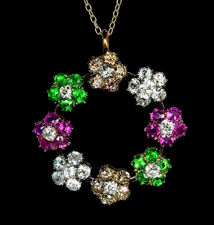 The pendant is designed as a floral wreath with four pairs of flowers set with sparkling gemstones, namely -  a pair of white diamond flowers (G-H color, VS2-SI2 clarity),  a pair of fancy golden-brown diamond flowers with white diamond centers,  a