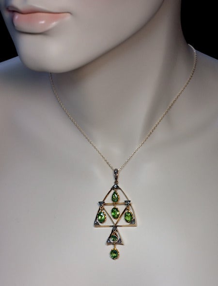 An Antique Demantoid, Diamond and Gold Pendant

Made in Moscow between 1899 and 1908

The pendant is designed in Russian Modern style of the early 20th century.

Height with bail - 64 mm (2 1/2 in.) 

A large gold triangular frame with two