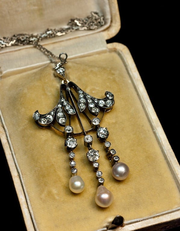 This elegant Russian Imperial era antique pendant necklace was made between 1908 and 1917.  

The necklace is designed as a pair of diamond-set stylized Art Nouveau leaves with three pearls hanging on diamond-set links.

 Handcrafted in silver