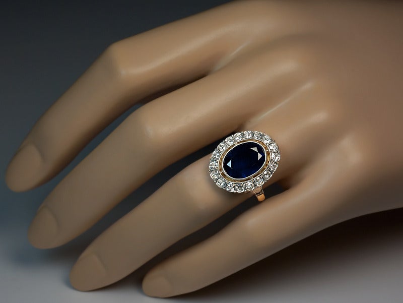 A platinum topped 14K yellow gold Belle Epoque ring is centered with an oval midnight blue sapphire (11.5 x 8.4 x 4.85 mm, approximately 3.75 ct) in a milgrain setting framed by 18 old single cut diamonds with an estimated combined weight of 0.90