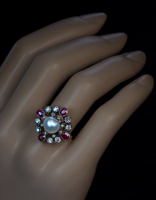 circa 1880

The ring features a natural 8.4 mm salt water pearl in an openwork silver topped 18Kt gold bezel.  The pearl is surrounded by two rows of gemstones: eight rose cut diamonds, eight old mine diamonds and four rubies.
Approximate total