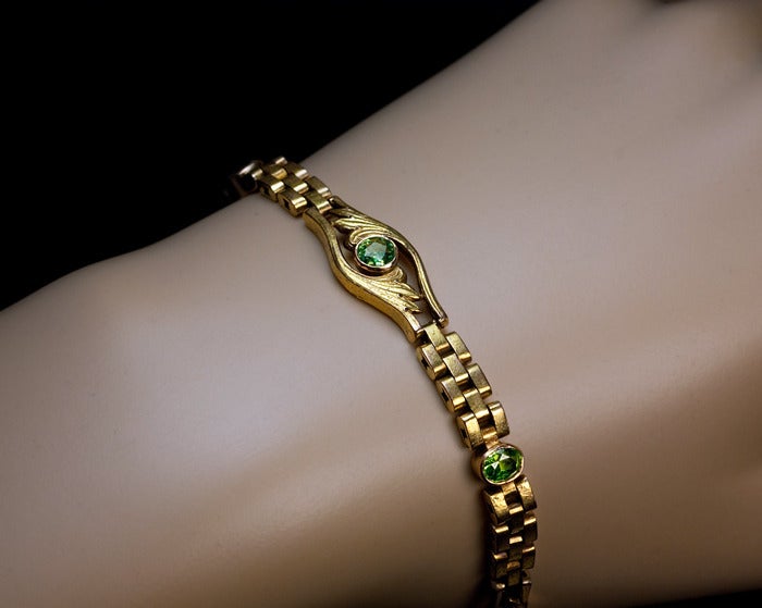 made in Moscow between 1908 and 1917

 A 14K greenish yellow gold bracelet with Art Nouveau style floral links is embellished with three demantoids.  

 The round demantoid is approximately 0.39 ct., estimated weight of two oval demantoids is