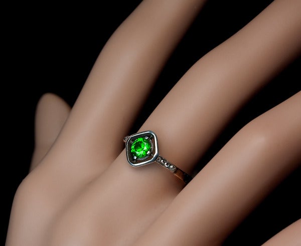 A silver and gold Art Deco ring features a vivid green Russian demantoid (4.55 x 2.7 mm, approximately 0.39 carats),  flanked by six rose cut diamonds, all set in silver over 14K gold.

 US ring size 5 1/4  (16 mm)