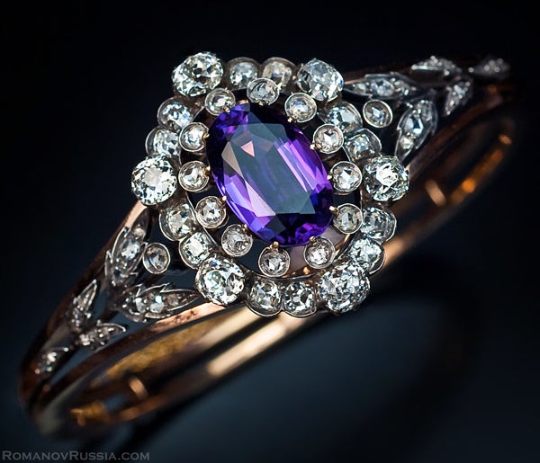 This very fine antique Russian silver and gold bangle bracelet was made between 1908 and 1917.
The front is mounted with a detachable panel set with a 12 ct oval Siberian amethyst. The amethyst is framed by two rows of chunky old cut diamonds