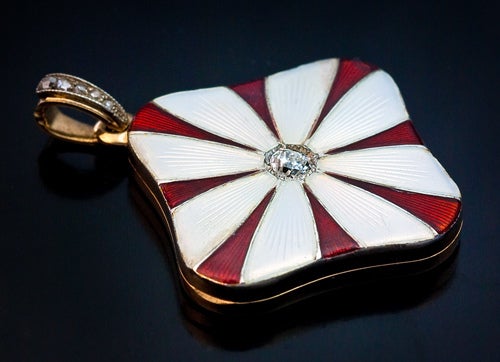 Made in St. Petersburg between 1908 and 1917

 The cover is enameled with a stylized daisy and set with an old mine diamond. The bail is encrusted with rose cut diamonds. The interior is fitted with two miniature picture frames. The back of the