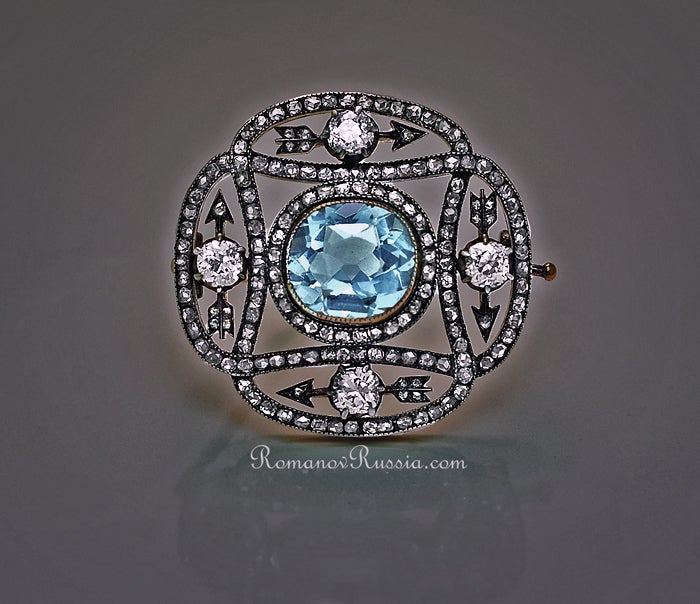 Designed as an open work plaque, the central collet-set aquamarine surrounded with four arrows forming a circle, each arrow highlighted with an old brilliant-cut diamond, the frame shaped as two interlaced loops set with rose-cut diamonds. 

The