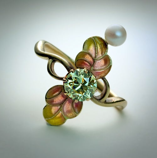 This very stylish Art Nouveau antique ring was made in Moscow between 1908 and 1917.

The ring is handcrafted in green gold and centered with an Old European cut fancy diamond of champagne color (approximately 0.85 ct) between two exotic